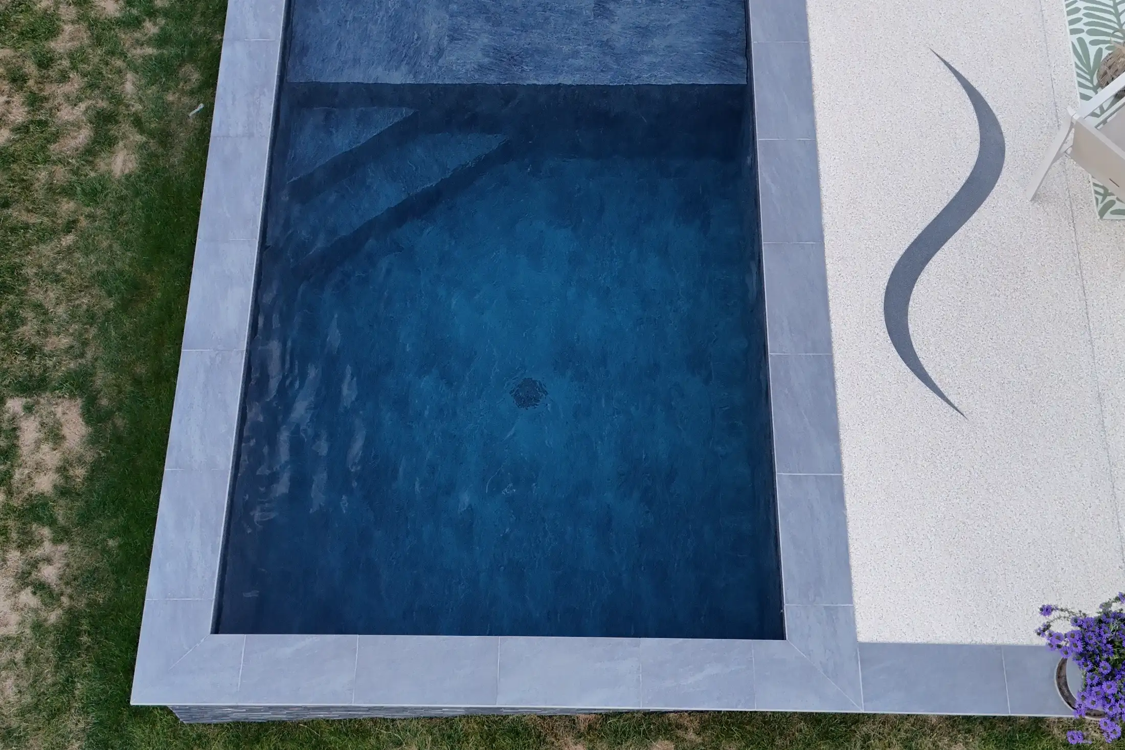 Piscine rectangulaire à membrane armée sombre, margelles en pierre grise