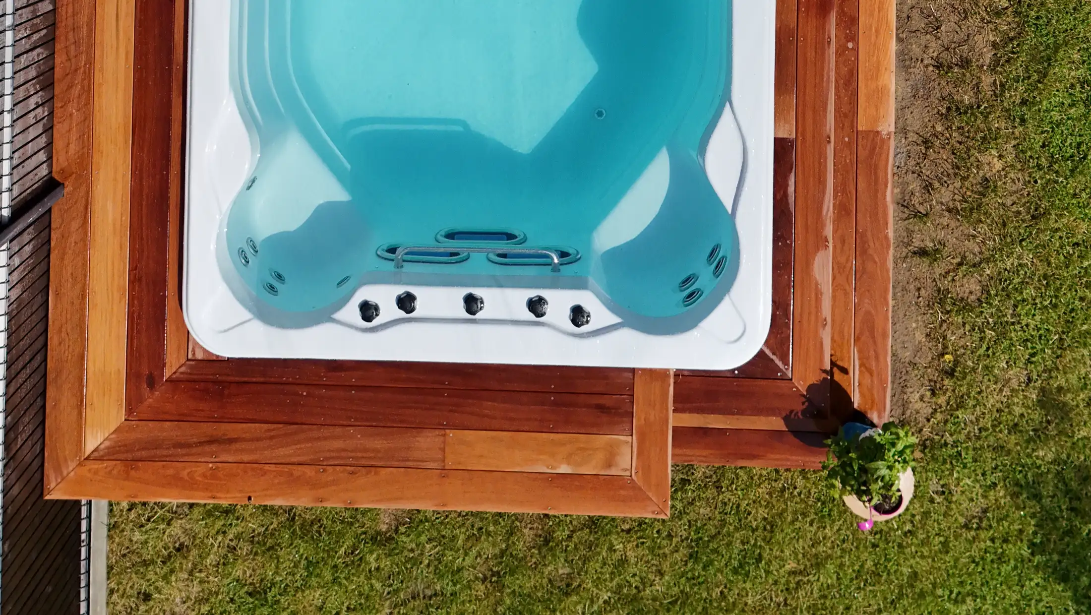 Spa de nage encastré au niveau d'une terrasse en bois exotique